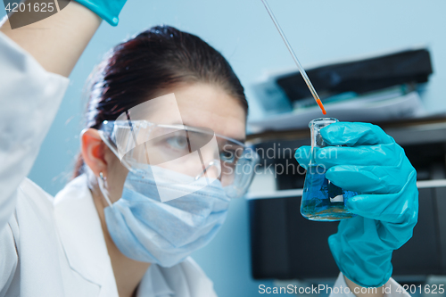 Image of Laboratorian with safety glasses, flask