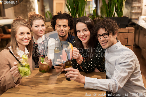 Image of happy friends with drinks at bar or cafe