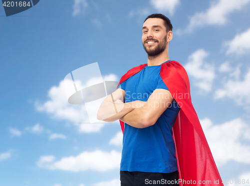 Image of happy man in red superhero cape over blue sky