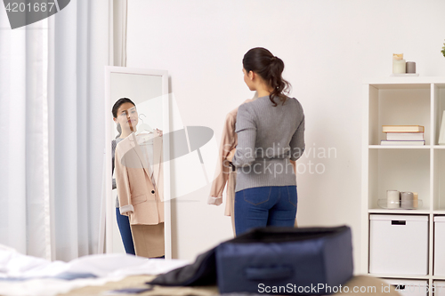 Image of woman packing travel bag at home or hotel room