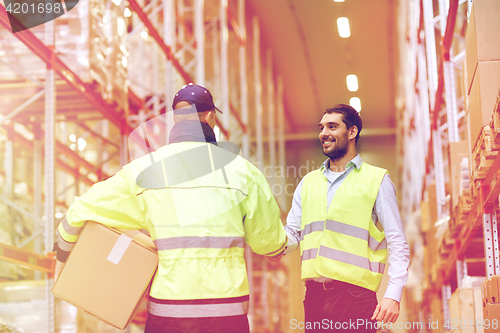 Image of men in safety vests shaking hands at warehouse