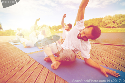Image of group of people making yoga exercises outdoors