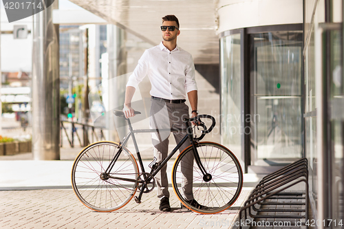 Image of young man parking his bicycle on city street