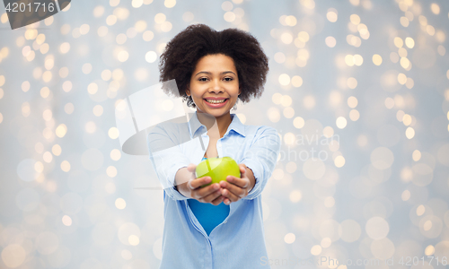 Image of happy african american woman with green apple