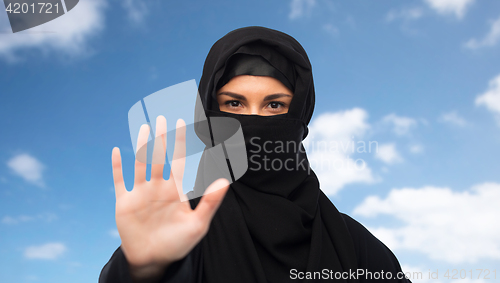 Image of muslim woman in hijab showing stop sign