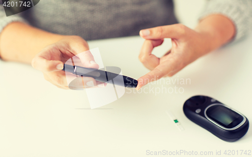 Image of close up of woman making blood test by glucometer