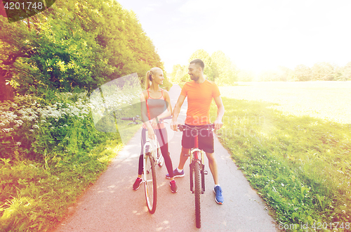 Image of happy couple riding bicycle outdoors