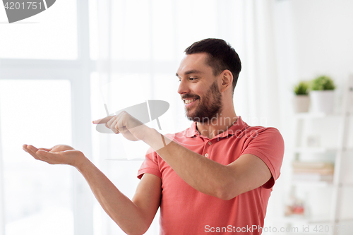 Image of happy man holding something imaginary at home