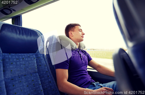 Image of happy young man sleeping in travel bus with pillow