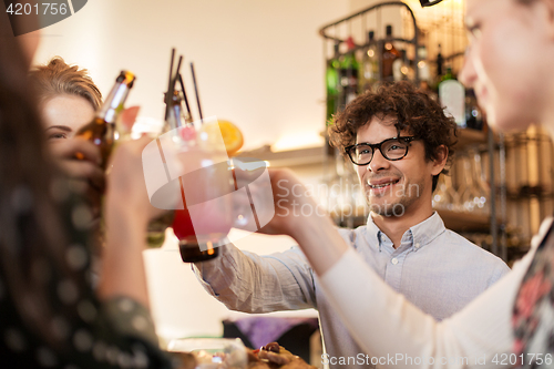 Image of happy friends clinking drinks at bar or cafe