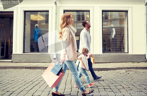 Image of happy family with child and shopping bags in city
