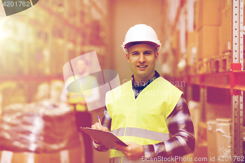 Image of man with clipboard in safety vest at warehouse