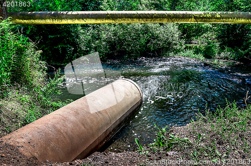 Image of Water flows from the pipe into the river.