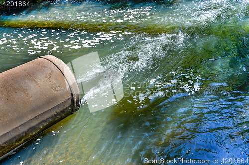 Image of Water flows from the pipe into the river.