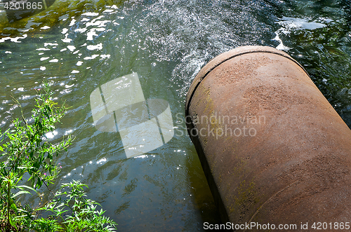 Image of Water flows from the pipe into the river.