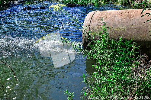 Image of Water flows from the pipe into the river.