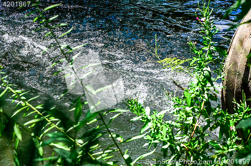 Image of Water flows from the pipe into the river.