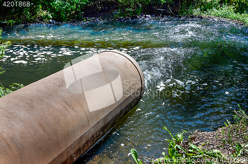 Image of Water flows from the pipe into the river.
