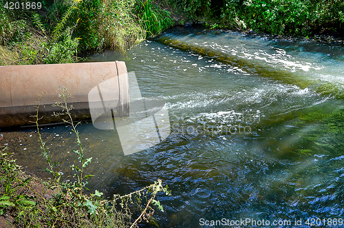 Image of Water flows from the pipe into the river.