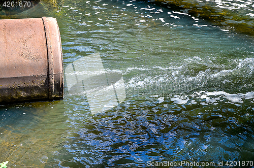 Image of Water flows from the pipe into the river.