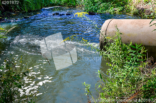 Image of Water flows from the pipe into the river.