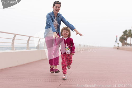 Image of mother and cute little girl on the promenade by the sea