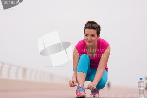 Image of Young woman tying shoelaces on sneakers