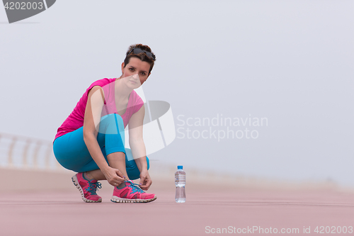 Image of Young woman tying shoelaces on sneakers