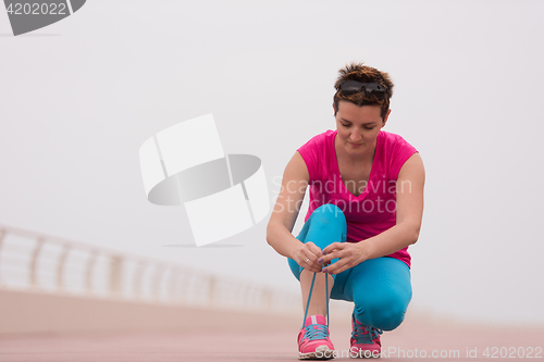 Image of Young woman tying shoelaces on sneakers