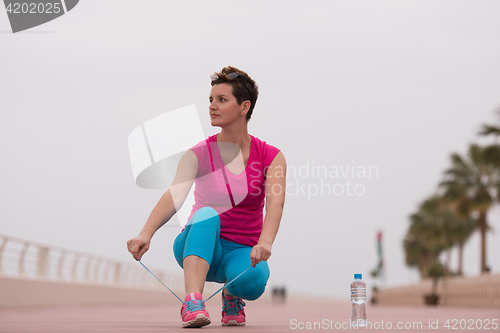 Image of Young woman tying shoelaces on sneakers