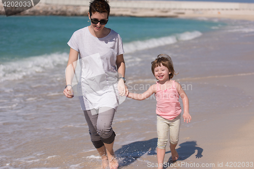 Image of mother and daughter running on the beach