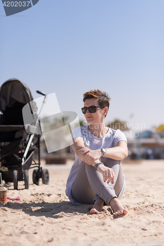 Image of Young mother with sunglasses relaxing on beach