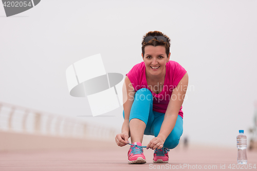 Image of Young woman tying shoelaces on sneakers