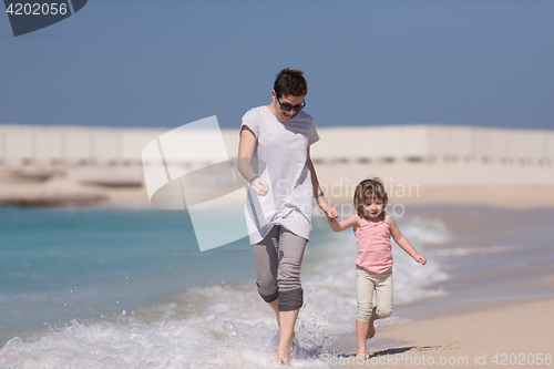 Image of mother and daughter running on the beach