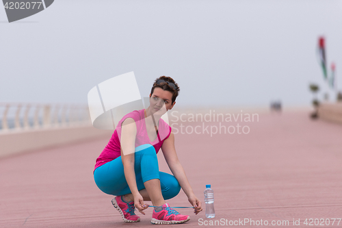 Image of Young woman tying shoelaces on sneakers