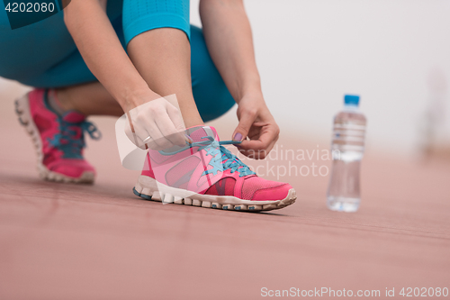 Image of Young woman tying shoelaces on sneakers