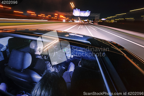 Image of couple of friends in a luxury car driving at night