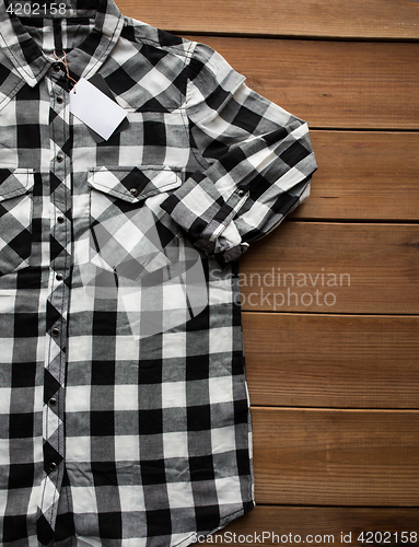 Image of close up of checkered shirt on wooden background