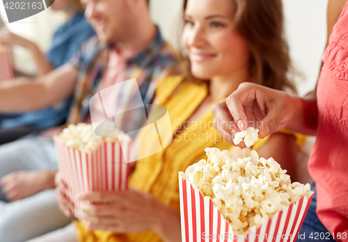 Image of close up of happy friends eating popcorn at home