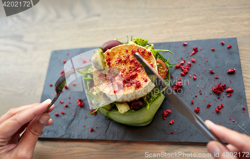 Image of woman eating goat cheese salad at restaurant