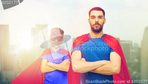 Image of man and boy wearing mask and red superhero cape