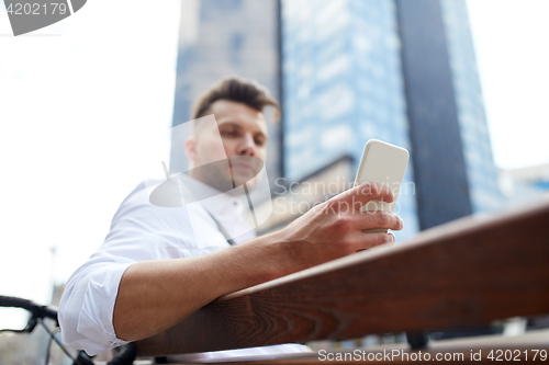 Image of close up of man texting on smartphone in city