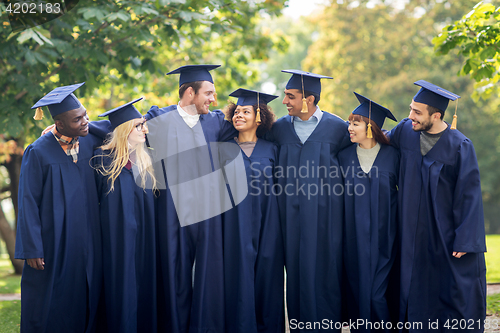 Image of happy students or bachelors in mortar boards