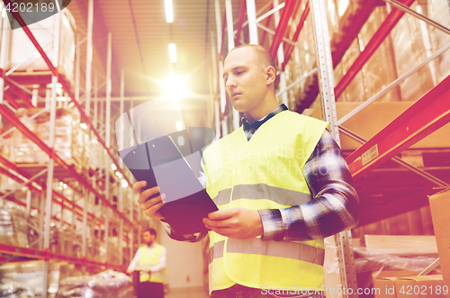 Image of man with clipboard in safety vest at warehouse