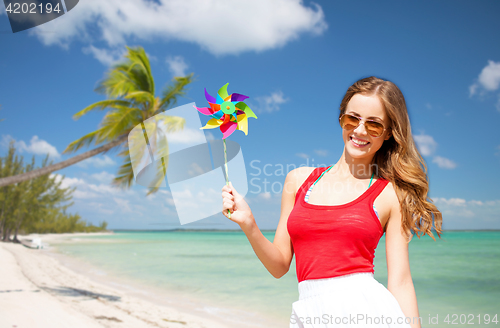 Image of happy young woman with pinwheel on summer beach