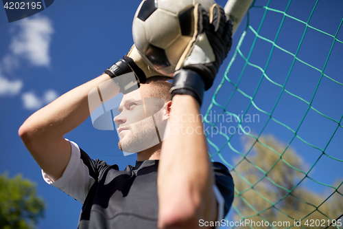 Image of goalkeeper with ball at football goal on field