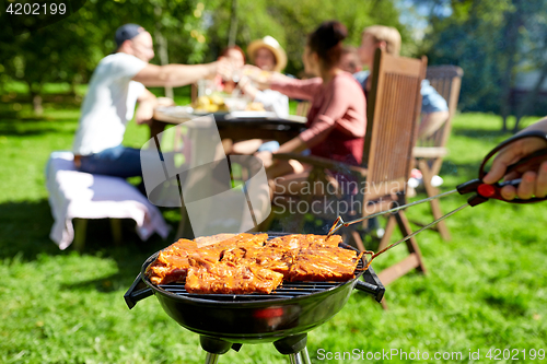 Image of man cooking meat on barbecue grill at summer party