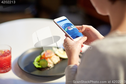 Image of woman with smartphone photographing food at cafe