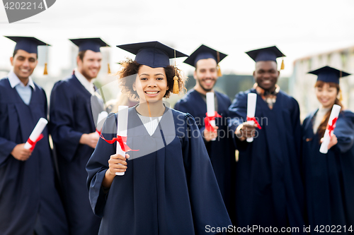 Image of happy students in mortar boards with diplomas