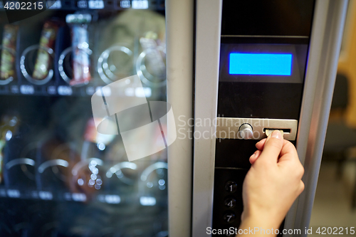Image of hand inserting euro coin to vending machine slot